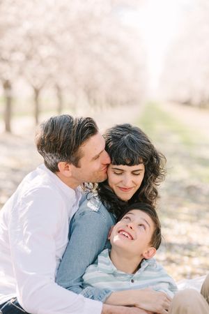 Family sharing loving embraces and laughter during an outdoor photo session.