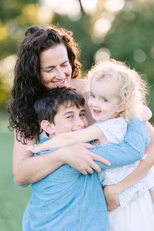 Warm family embrace captured outdoors with soft bokeh background.