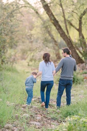 Family walking together through a scenic wooded path on an autumn day.