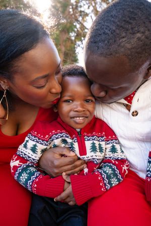 A loving family moment captured in matching red and white Nordic print Christmas sweaters during a holiday photoshoot.