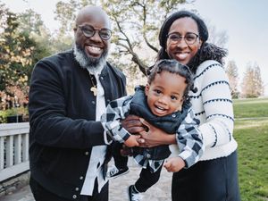 A joyful family shares warm embraces and laughter while taking outdoor photos in a park setting.