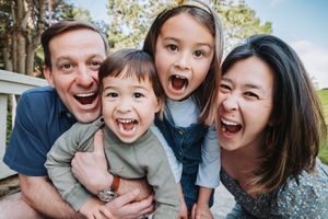 Family members laughing together during an outdoor photo session with playful expressions and casual attire.