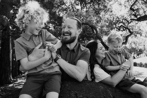 A series of black and white photos showing a couple laughing and embracing outdoors in a natural setting.