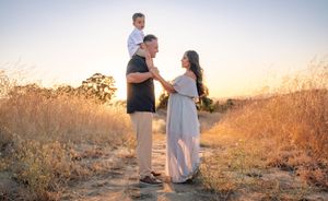 A couple stands together in a golden field during sunset while sharing intimate moments in a romantic photoshoot.