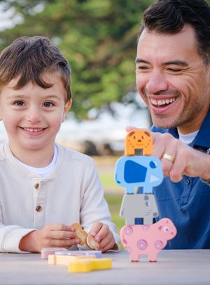 Parent and child playing with colorful wooden animal toys while sitting at table together.