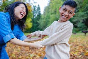 Couple playfully throwing autumn leaves in a park on a sunny fall day.