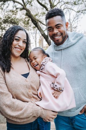 A couple shares joyful moments together outdoors while wearing cozy sweaters in soft pink and gray tones.