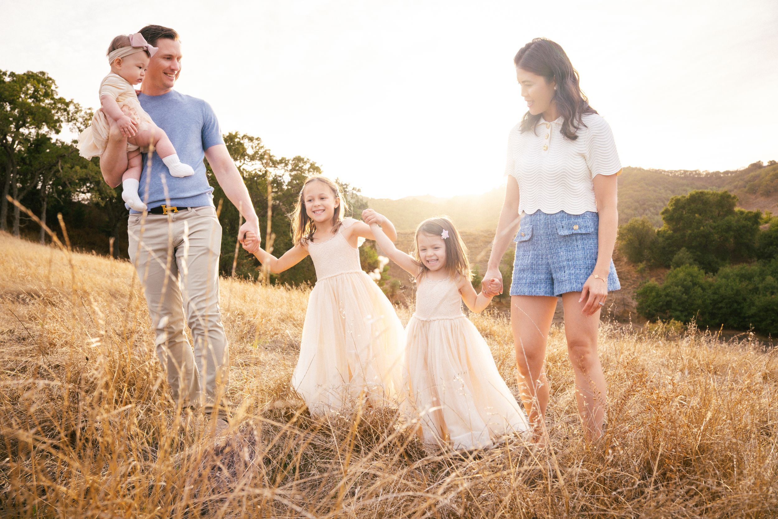 Family walking together through golden field at sunset holding hands and enjoying nature.