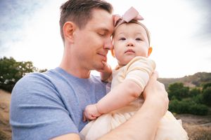 A tender moment between parent and baby during an outdoor photo session at sunset.