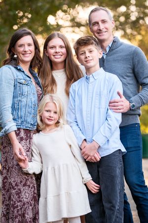 A group wearing coordinated blue and white outfits poses together outdoors during golden hour.