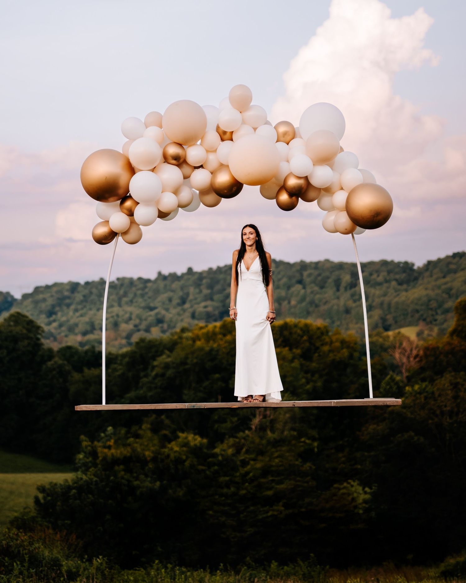 Girl standing on board held by balloons in the sky
