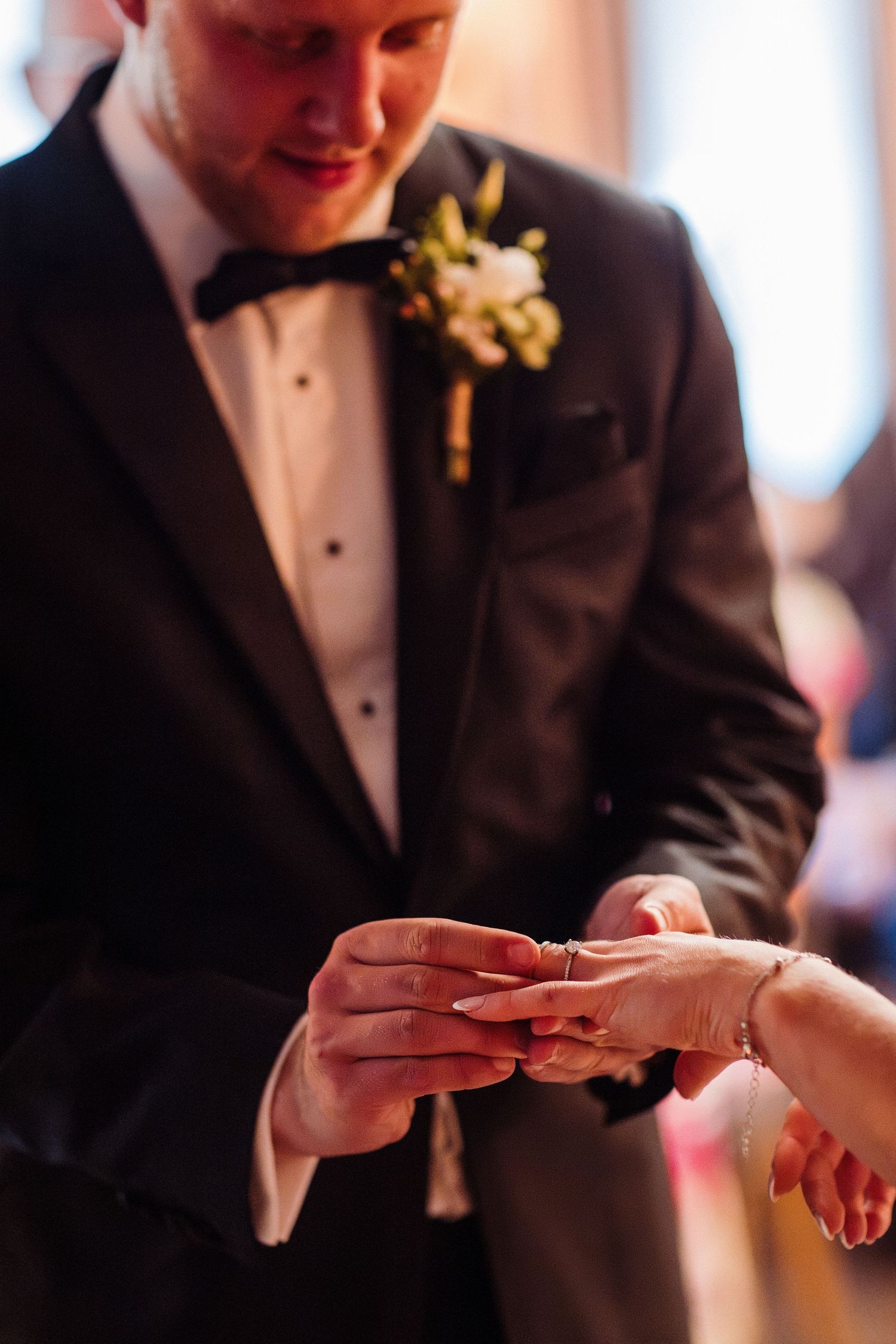 Close-up shots of hands exchanging wedding rings during a formal ceremony.
