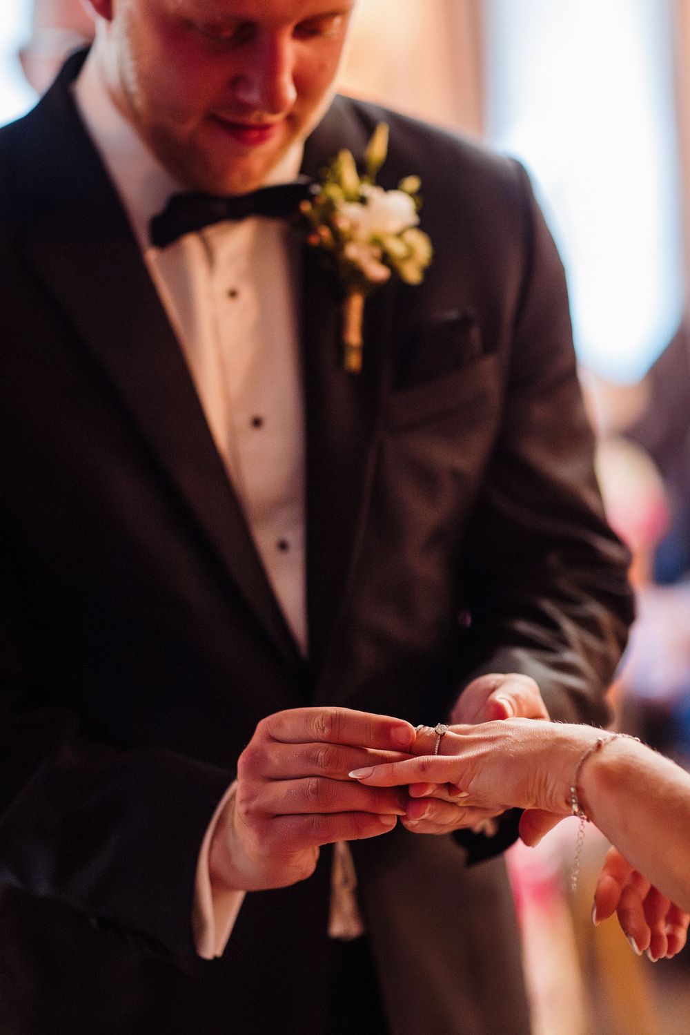 Close-up shots of hands exchanging wedding rings during a formal ceremony.