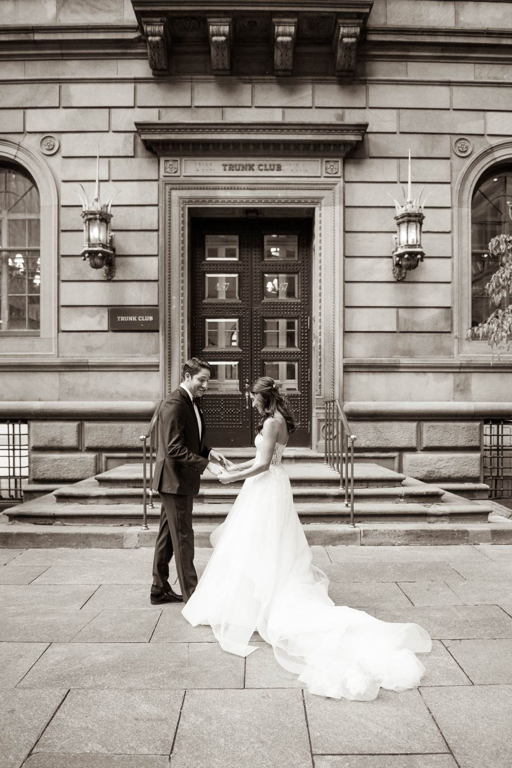 Elegant wedding couple standing in front of historic Tudor Club entrance with ornate architecture.