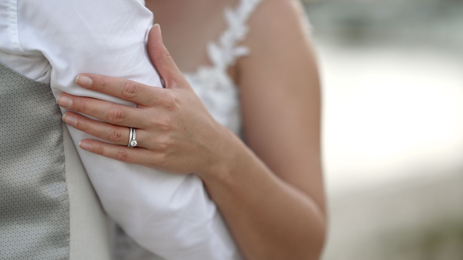 Close-up of hands displaying an engagement ring with soft focus background.