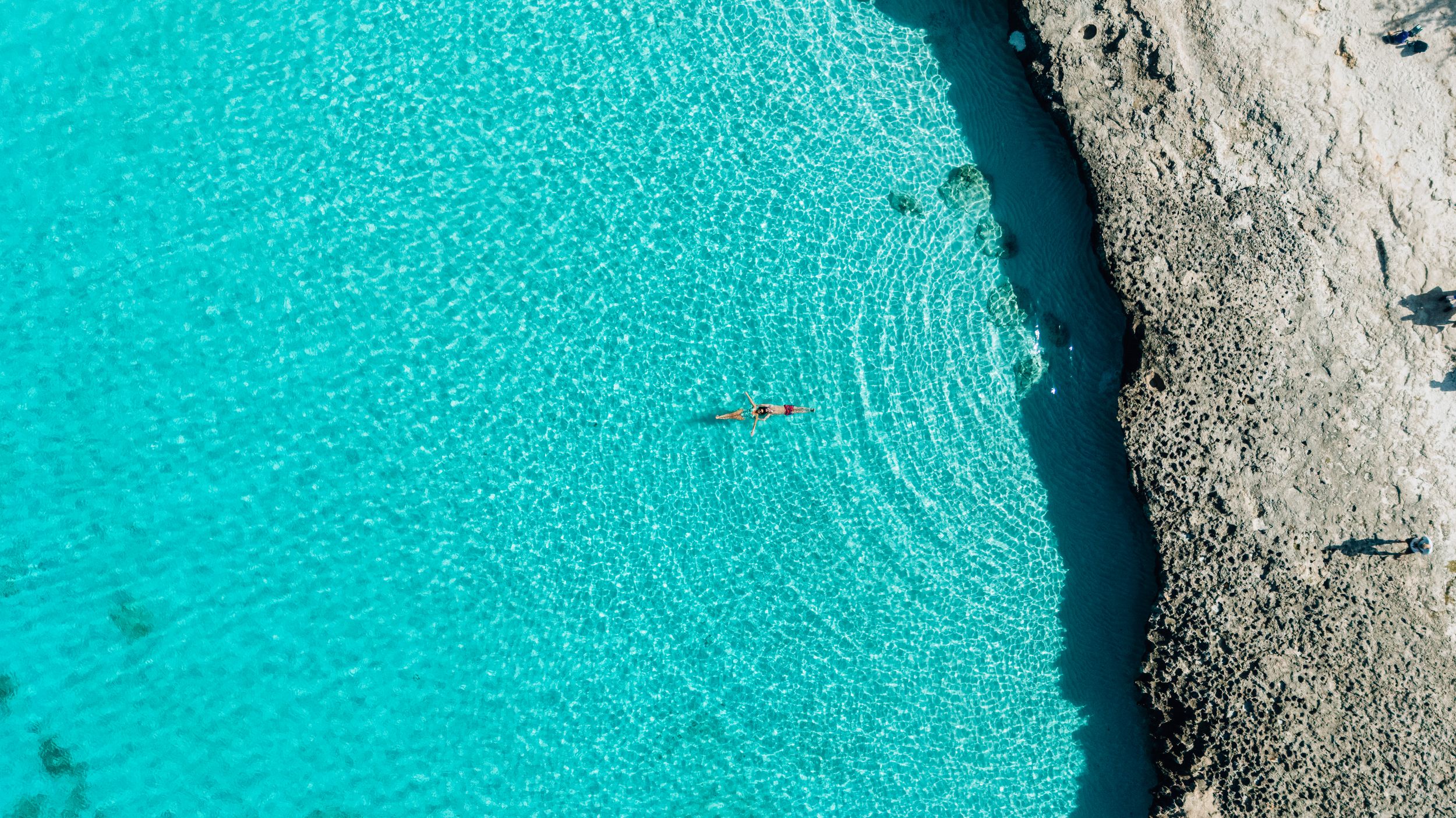 Stunning turquoise blue waters meet rugged limestone cliffs in a scenic coastal seascape.