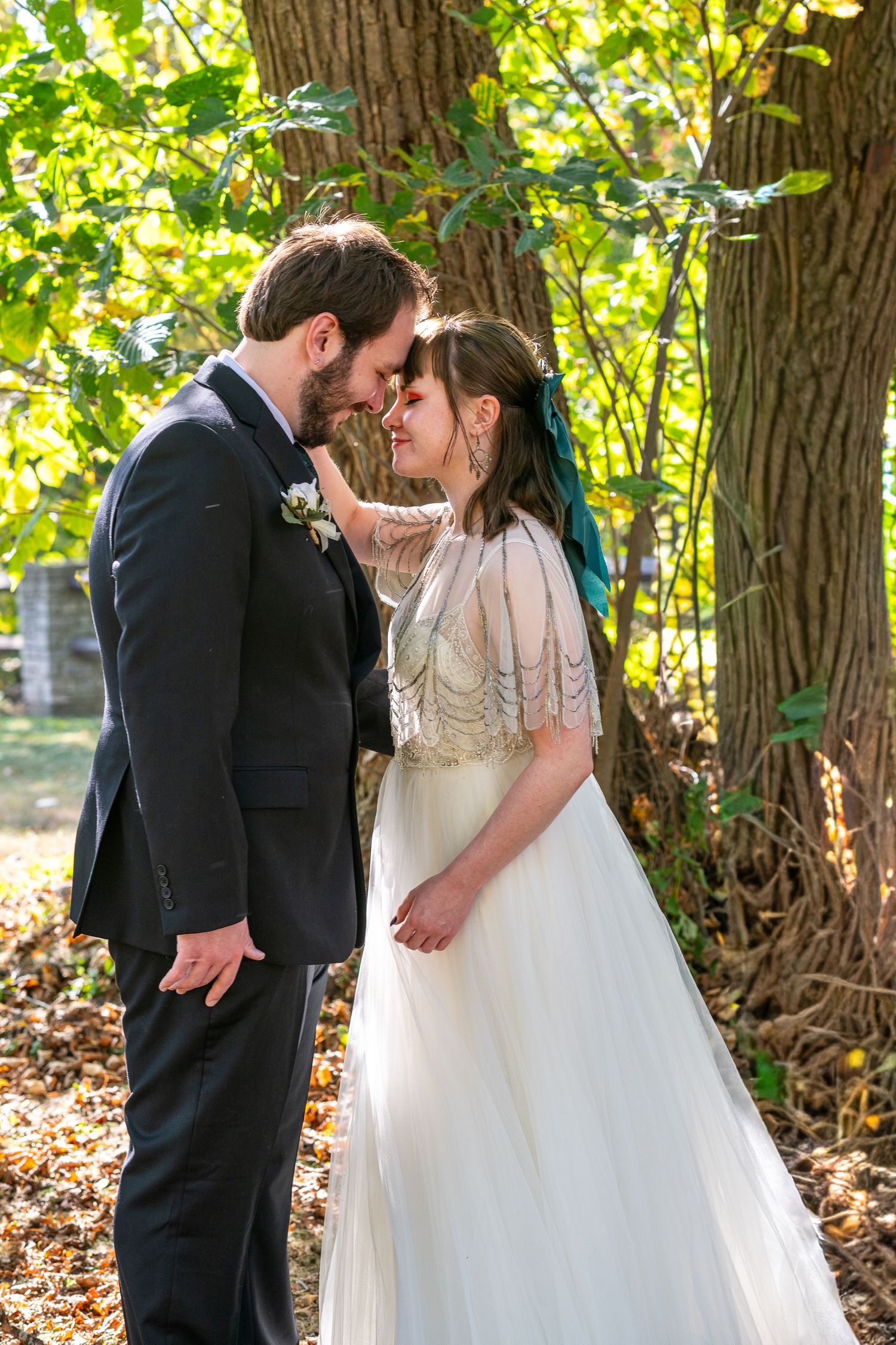 A romantic sequence of wedding photos showing a couple sharing tender moments beneath autumn trees in a natural setting.