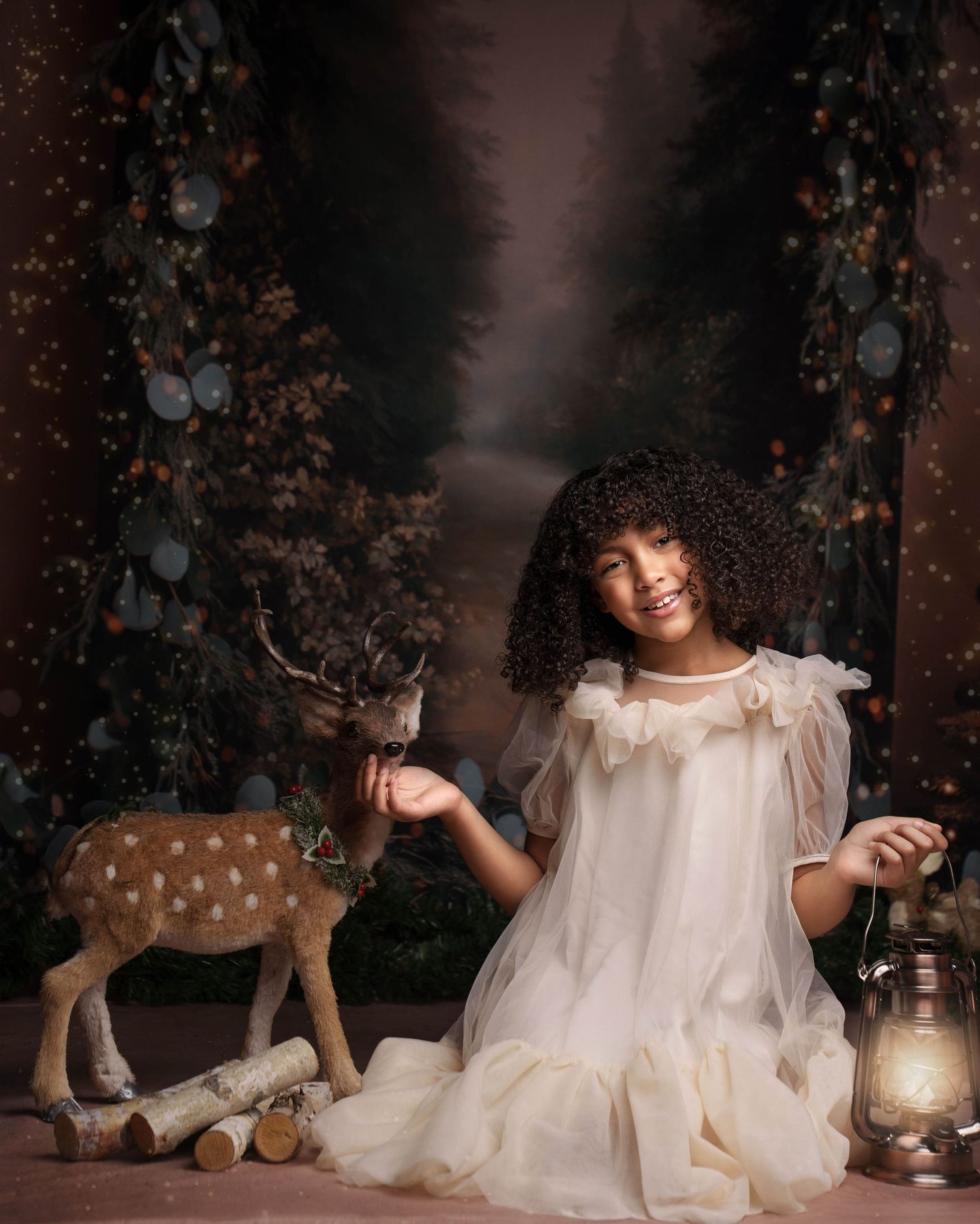 A magical Christmas themed photo series with a white dress, vintage lantern, and stuffed reindeer against a dark backdrop.