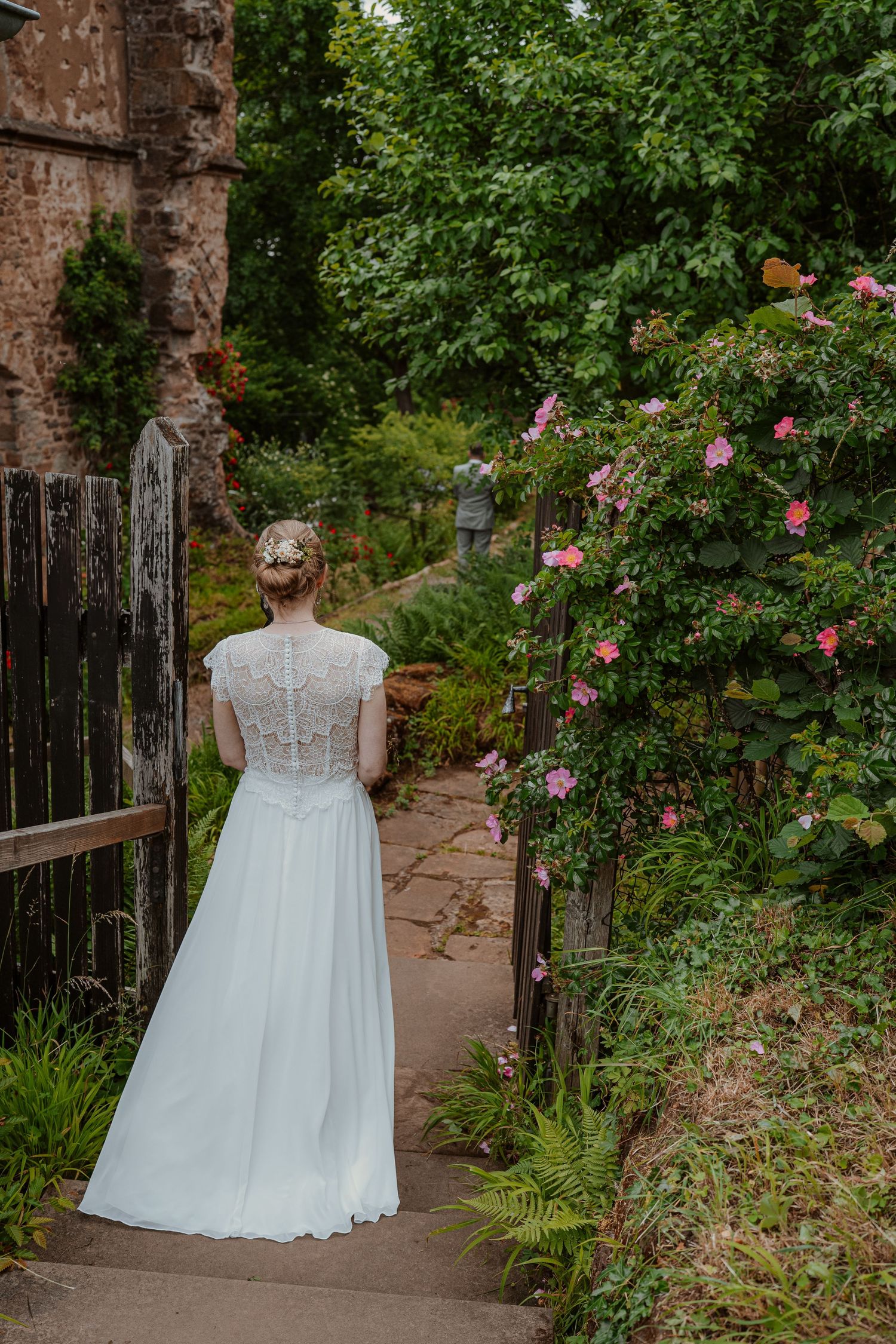 A romantic couple in white clothing shares an intimate moment in a wooded setting during golden hour.