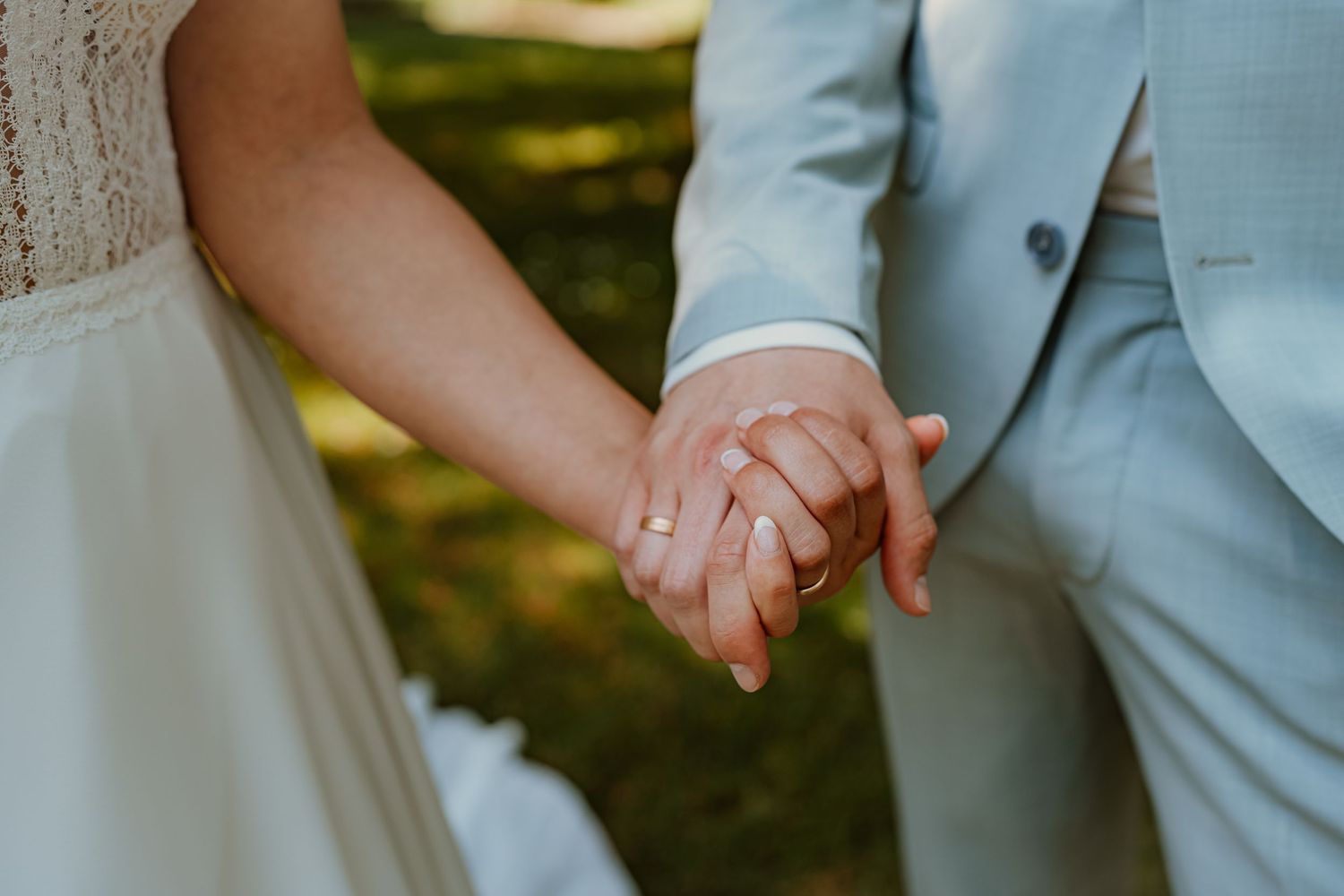 A romantic couple in white clothing shares an intimate moment in a wooded setting during golden hour.