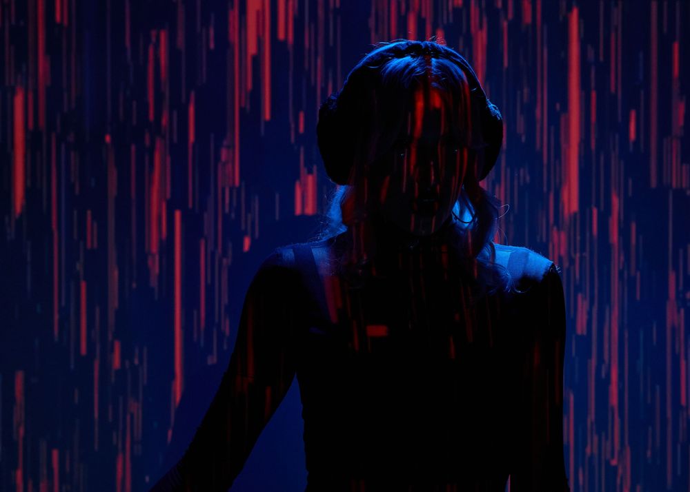 Silhouette of a person wearing headphones against a dark background with glowing red and blue streaks of light.
