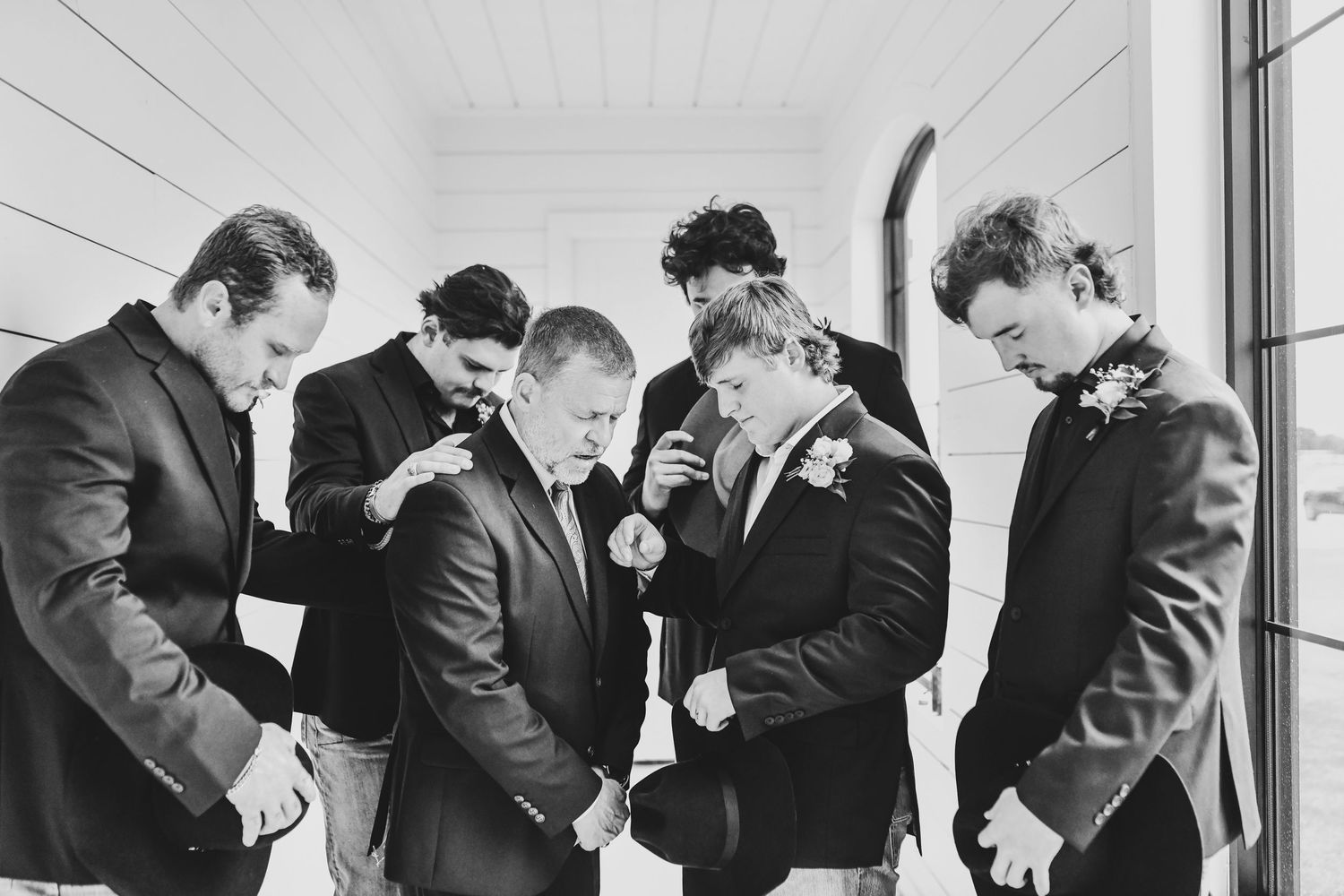 Groom sharing prayer with groomsmen before wedding