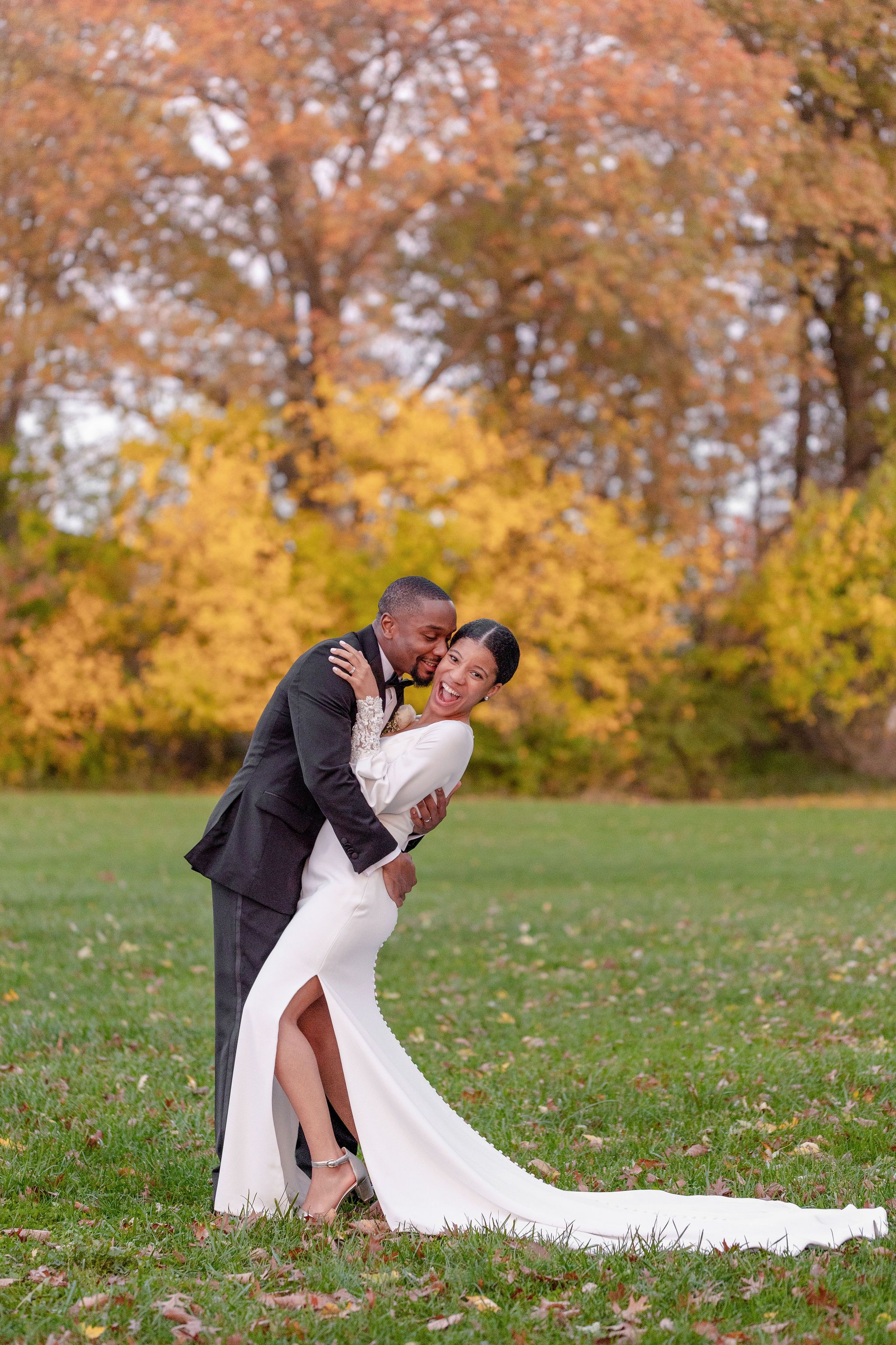 A romantic autumn wedding photograph with fall foliage creating a colorful backdrop.