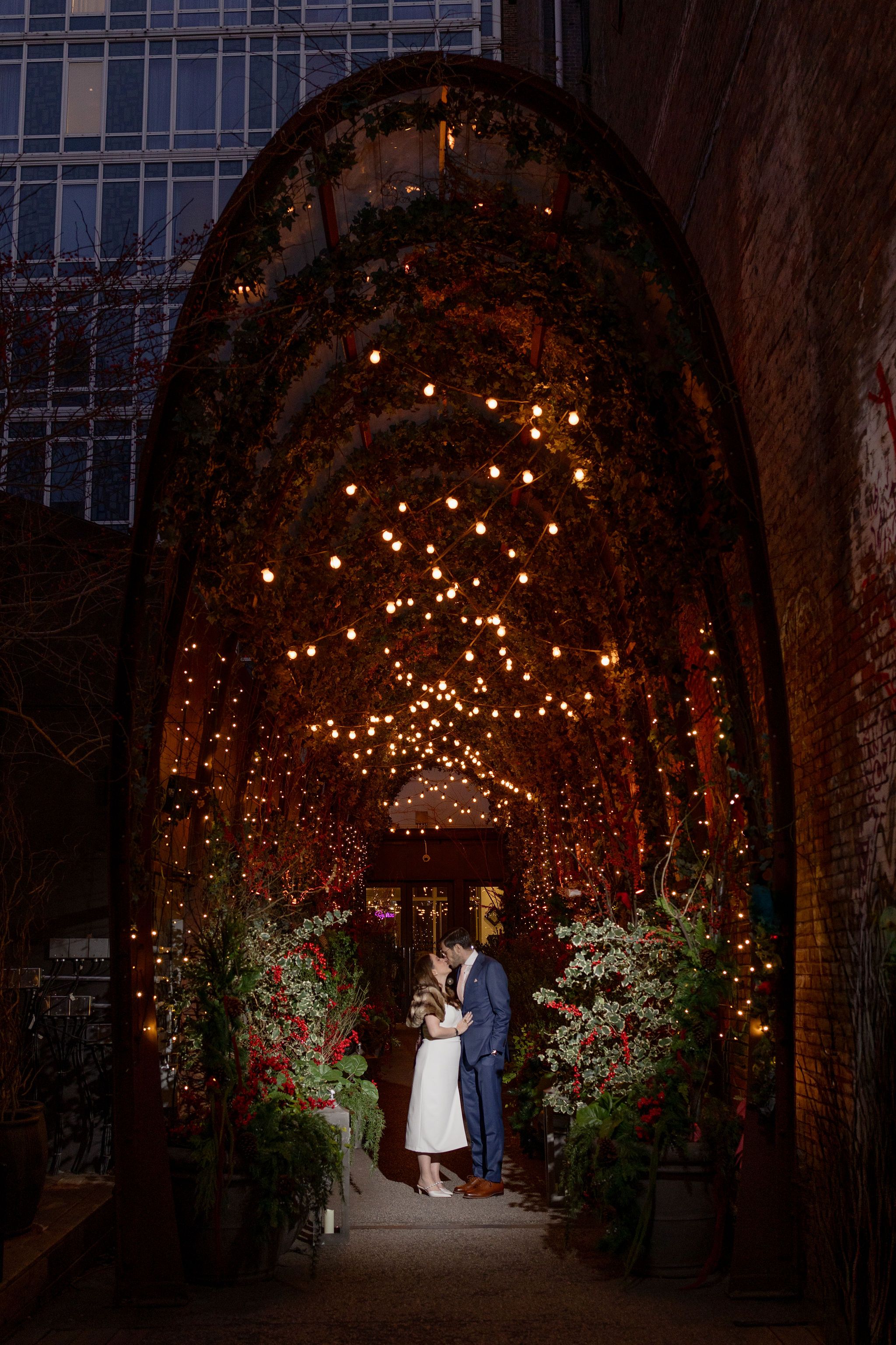 Romantic archway lit with string lights creates a magical wedding moment.