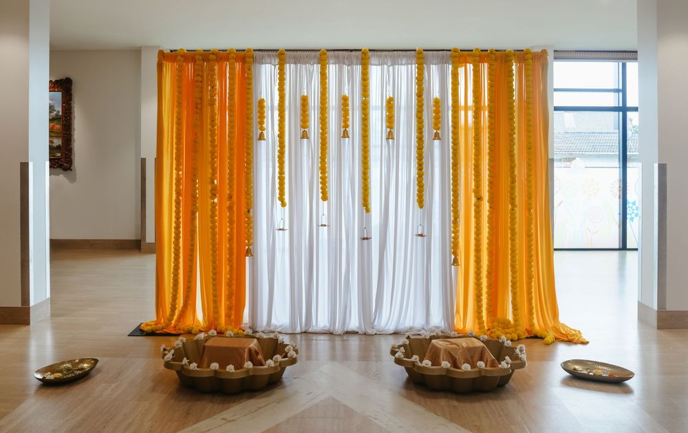 Orange and white draped curtains installation with golden decorative bowls on wooden floor in gallery.