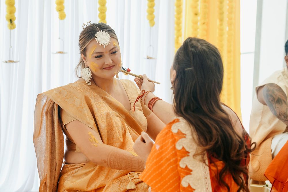 Bride in golden saree gets makeup done during traditional Indian wedding ceremony.