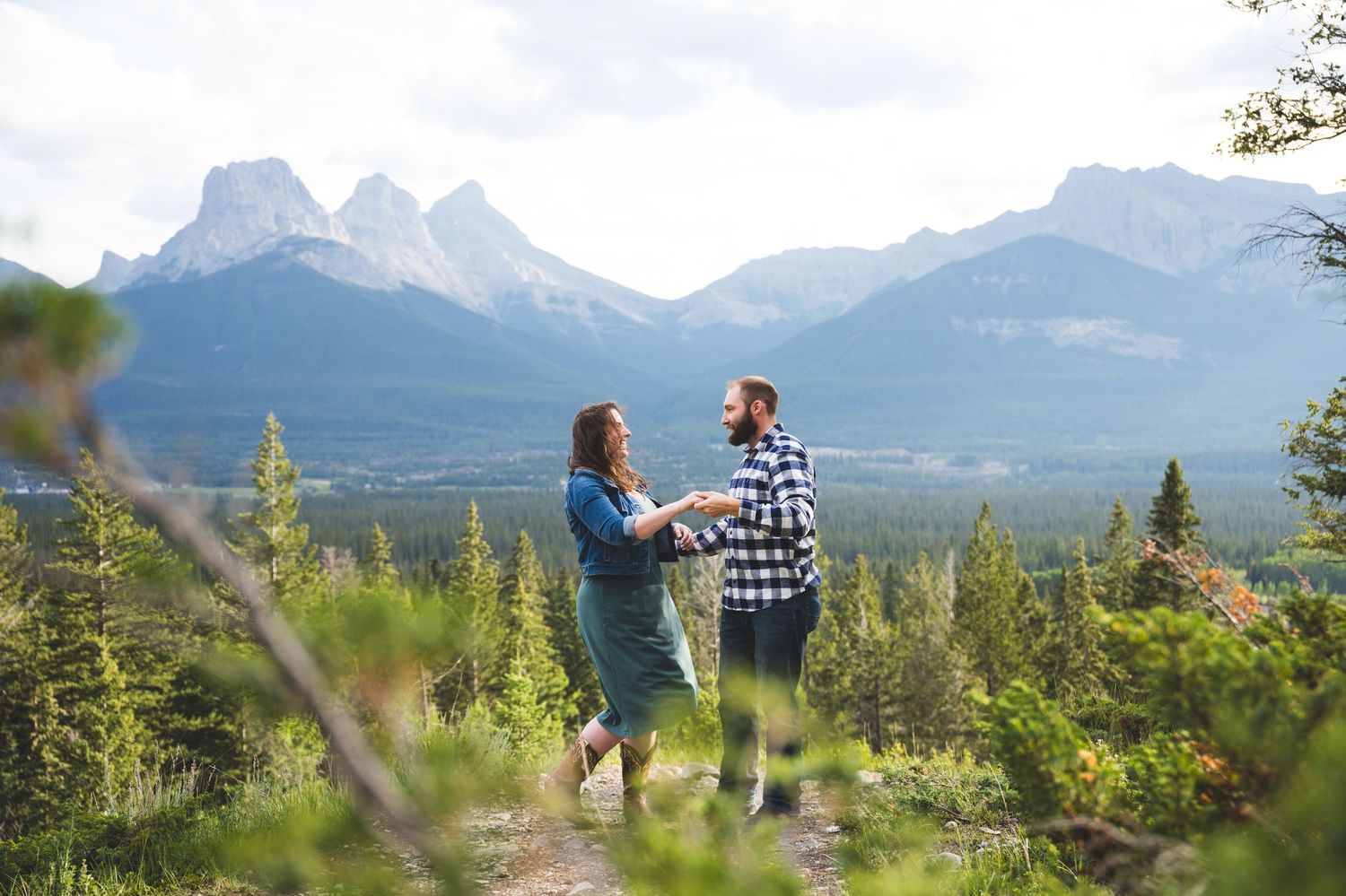 Romantic silhouette of a couple kissing against a dramatic mountain sunset sky.