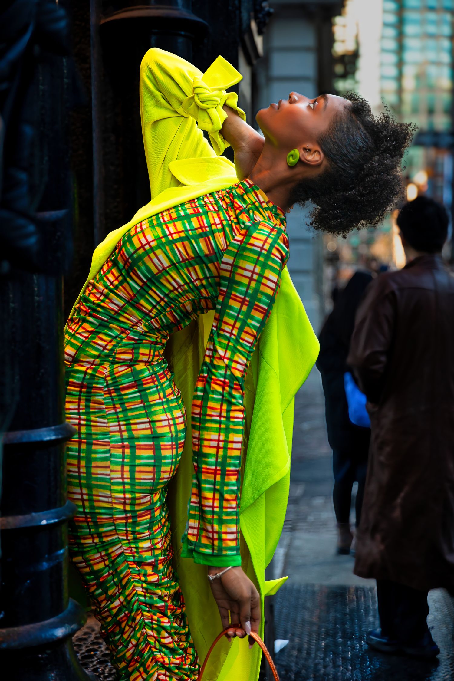 Expressive fashion pose showing vibrant yellow coat with traditional African print clothing.