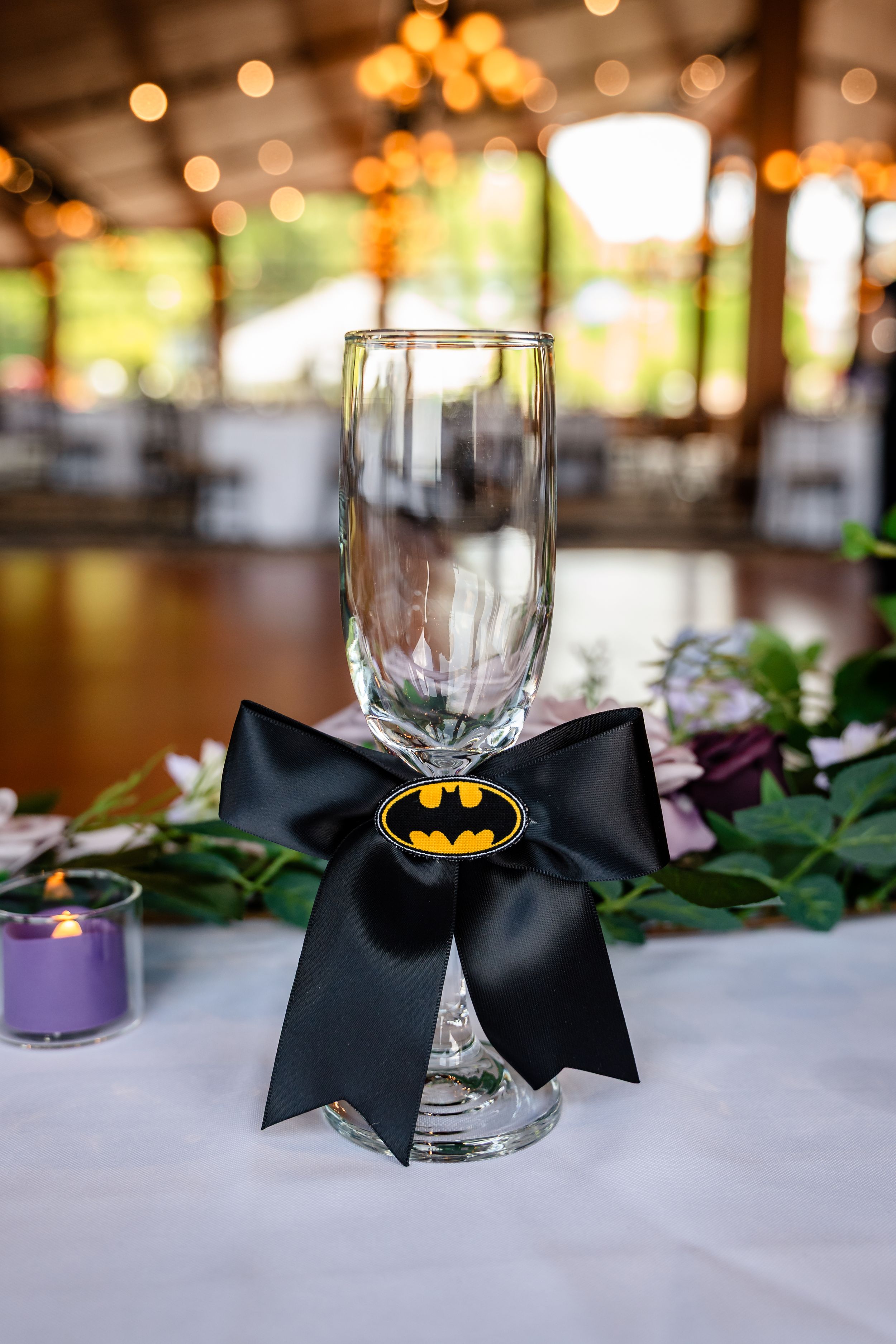 Elegant champagne flute decorated with a black Batman bow tie centerpiece on a wedding reception table.