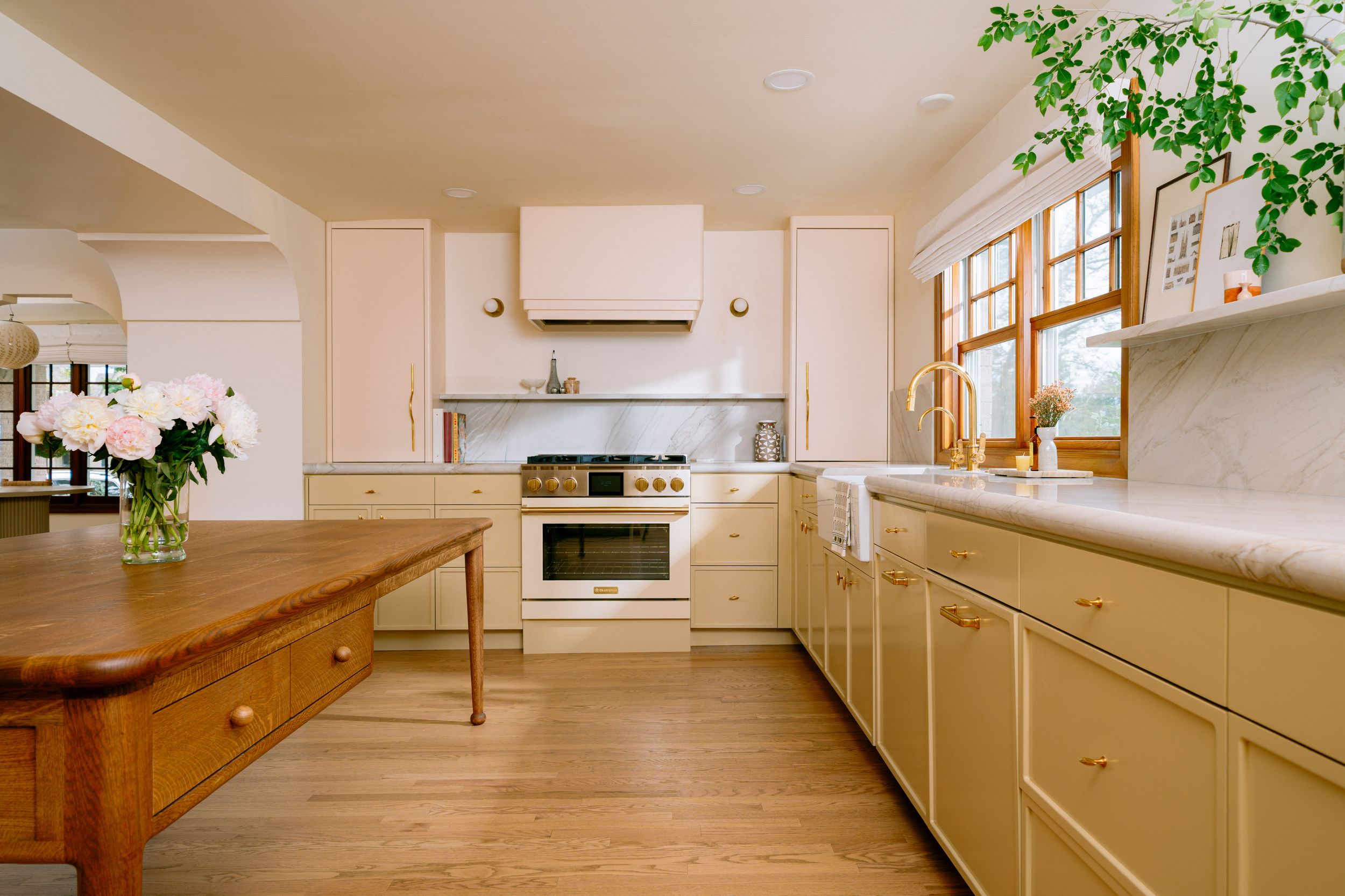 Modern kitchen interior with wood cabinets, red backsplash, and pendant lights over dark wooden table.