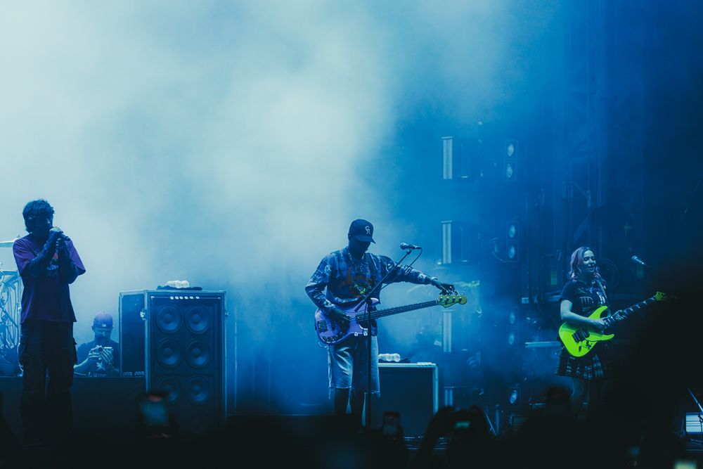 Band performing on stage in blue smoky light, guitarists playing electric guitars at a live concert.
