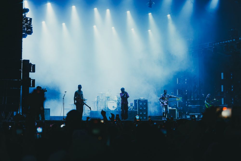 Band performing on a fog-filled stage with blue spotlights at a live concert venue.