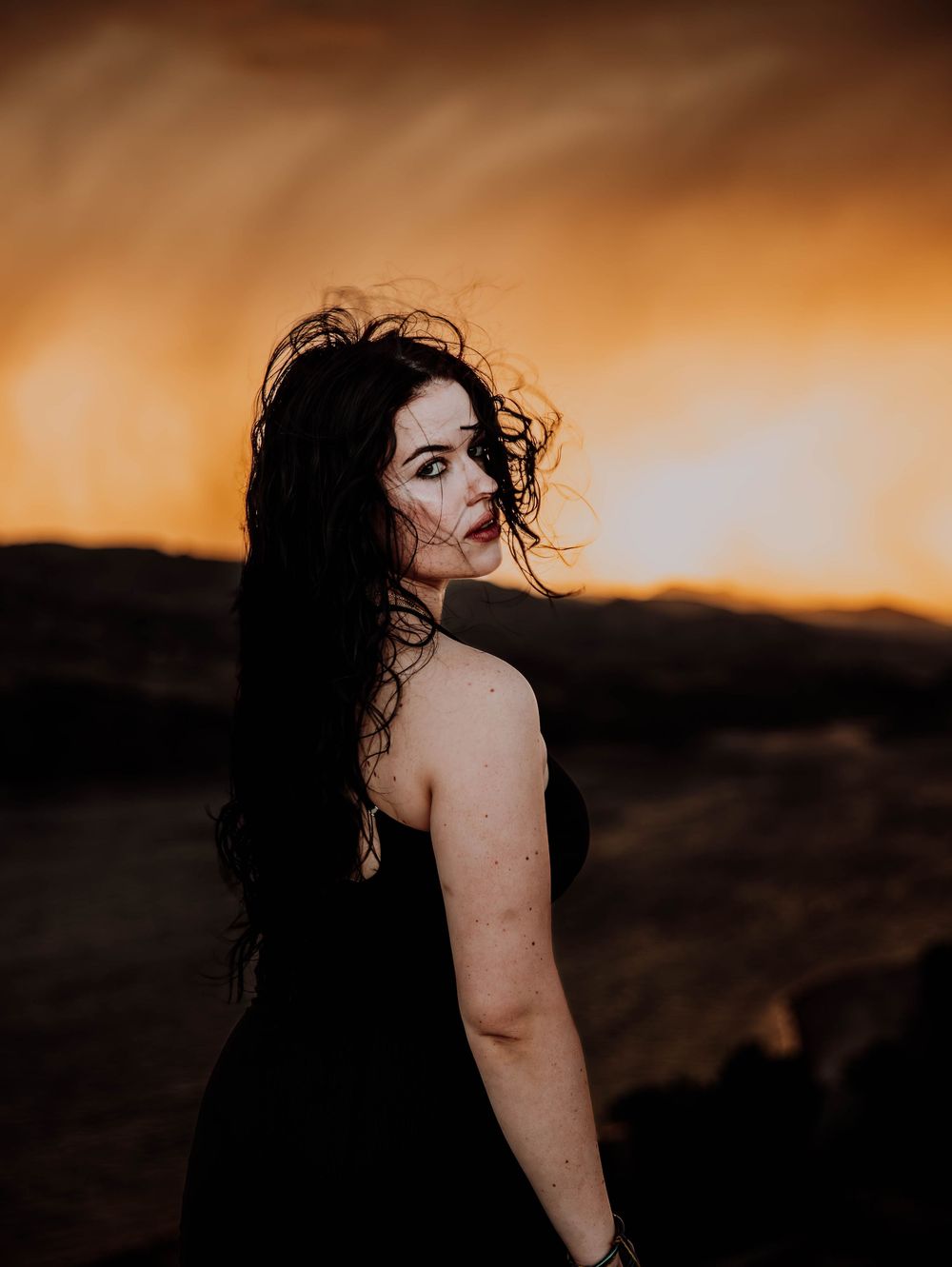 Woman poses in front of dramatic, cinematic sky for portrait and modeling photos in Fort Collins, Colorado