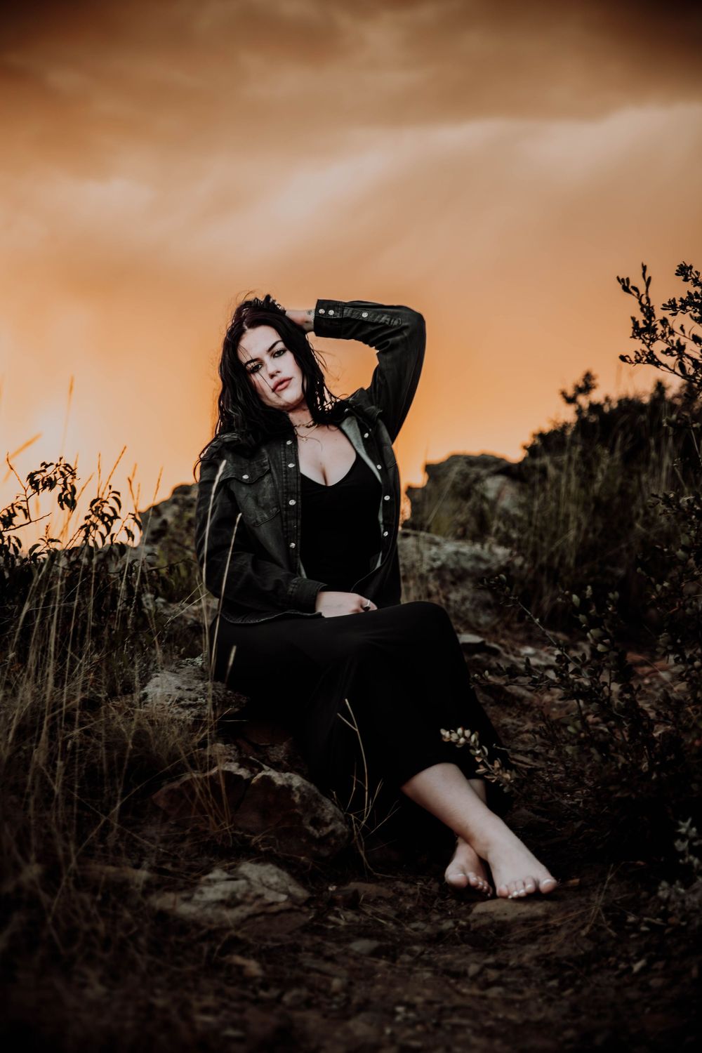 Woman sits and poses in front of dramatic, cinematic sky for portrait and modeling photos in Fort Collins, Colorado