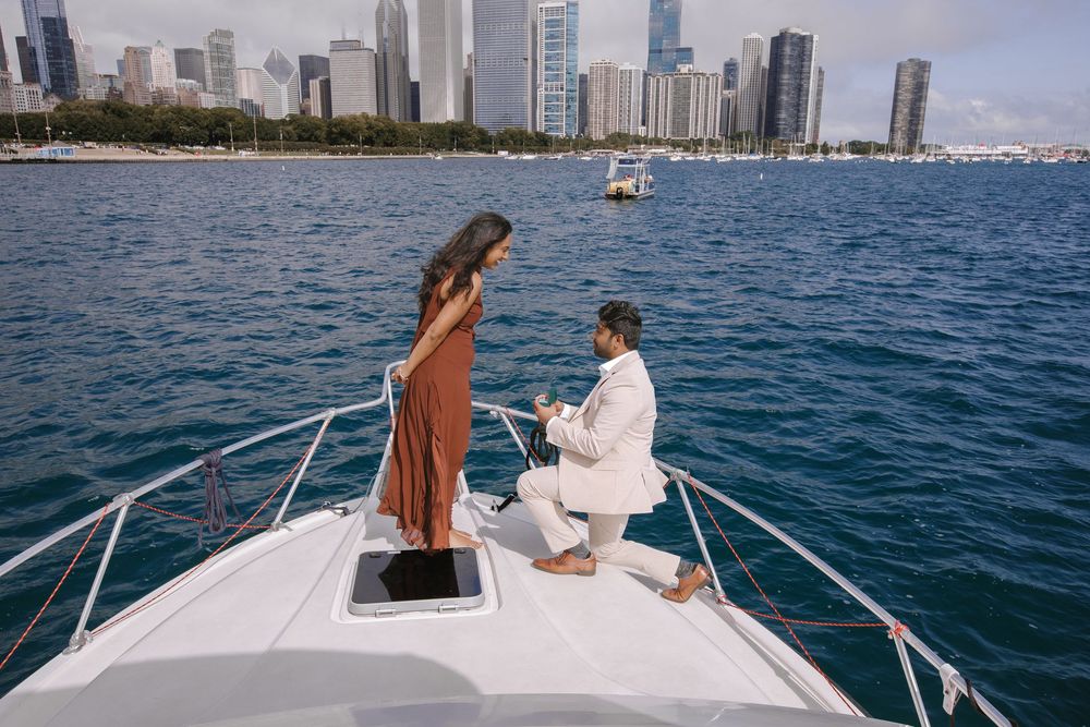 Man proposing to woman on yacht bow with Chicago skyline in background on a beautiful day.