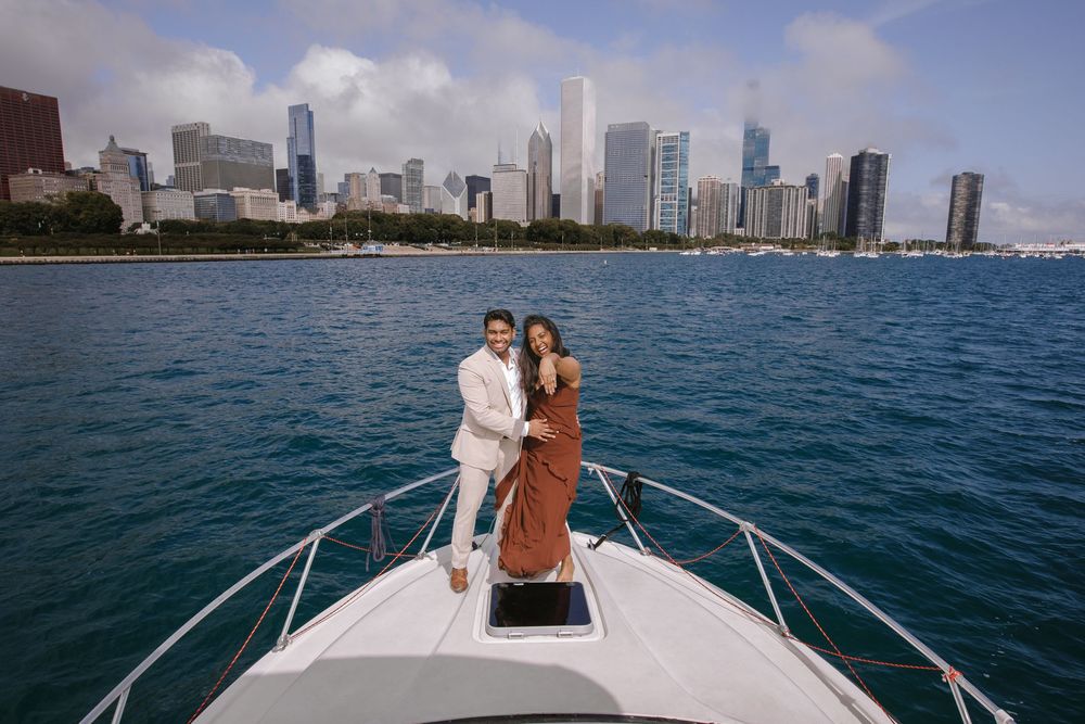 Couple posing on the bow of a yacht with Chicago skyline and blue water in the background.