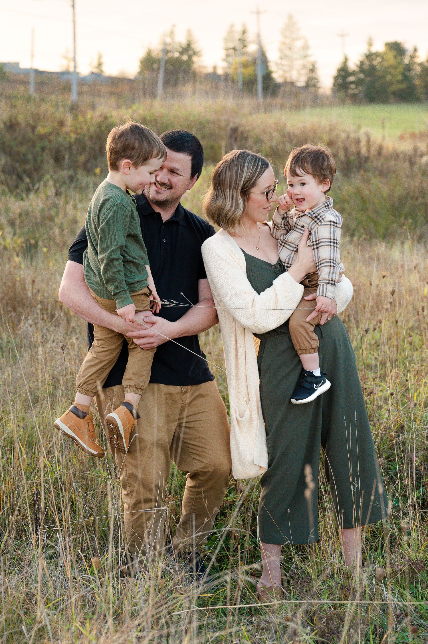 Mom and Dad holding children during golden hour in a field of long grass during a fall family session