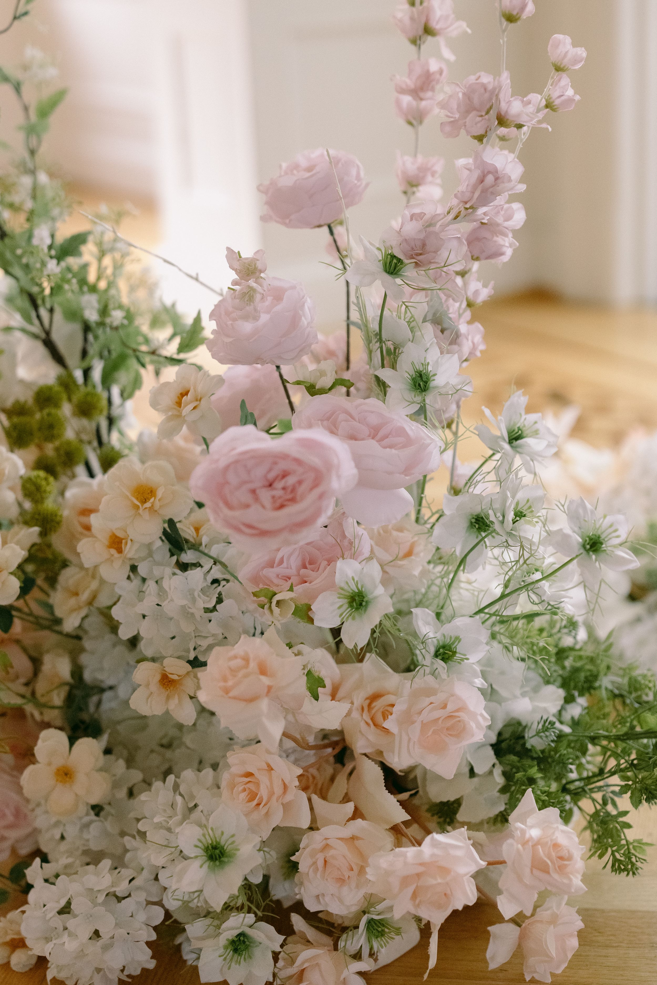 Elegant floral arrangement featuring soft pink roses, white blooms, and delicate greenery in a romantic pastel wedding bouquet.