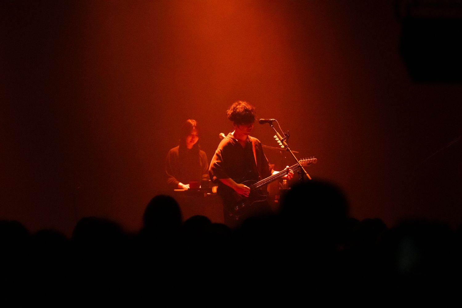 TK from Ling Tosite Sigure stands on stage under red light playing his guitar in front of a crowd at the Belasco.