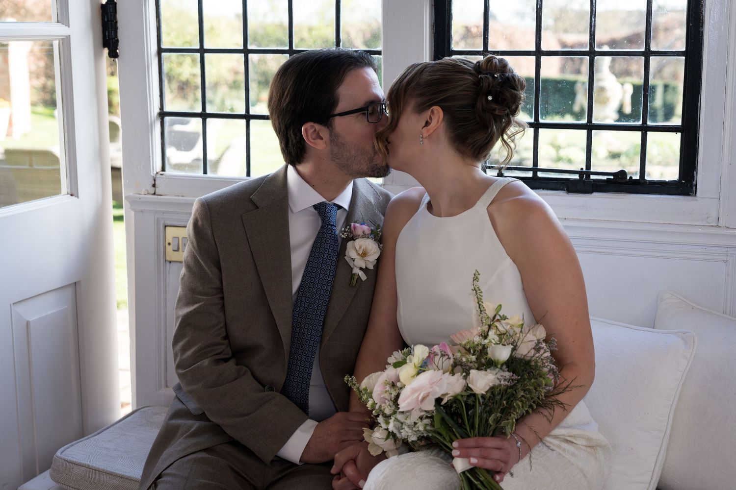 A romantic wedding photo series showing a couple in formal attire embracing outdoors against a natural backdrop.