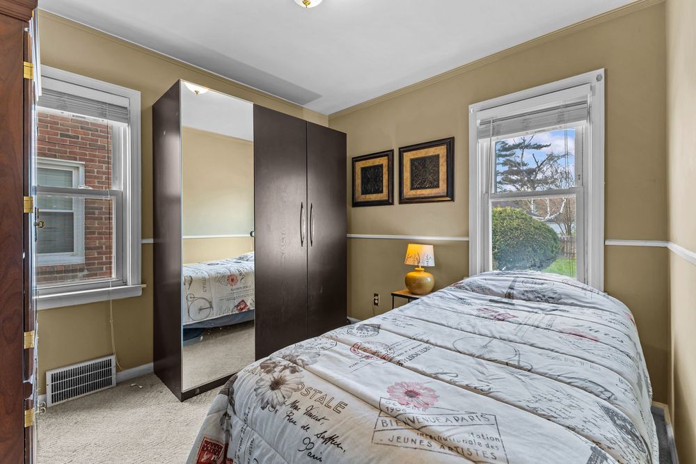 Cozy bedroom with large wardrobe, ceiling window, and patterned bedspread on a full-size bed.
