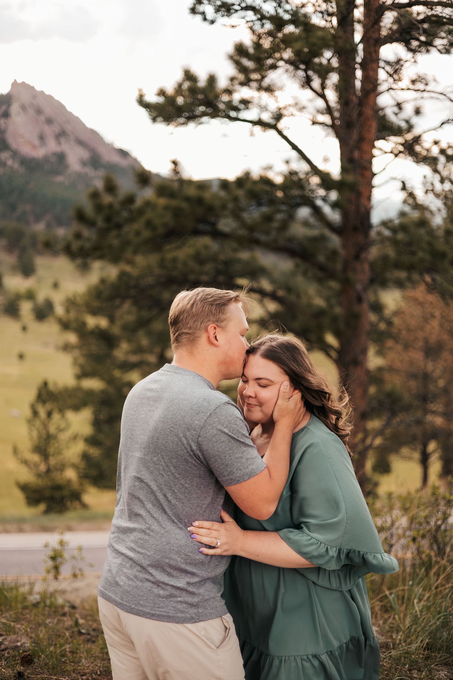 Couple sharing a tender moment outdoors with Rocky Mountain scenery|  Baby Announcement Photographer in Boulder, Colorado