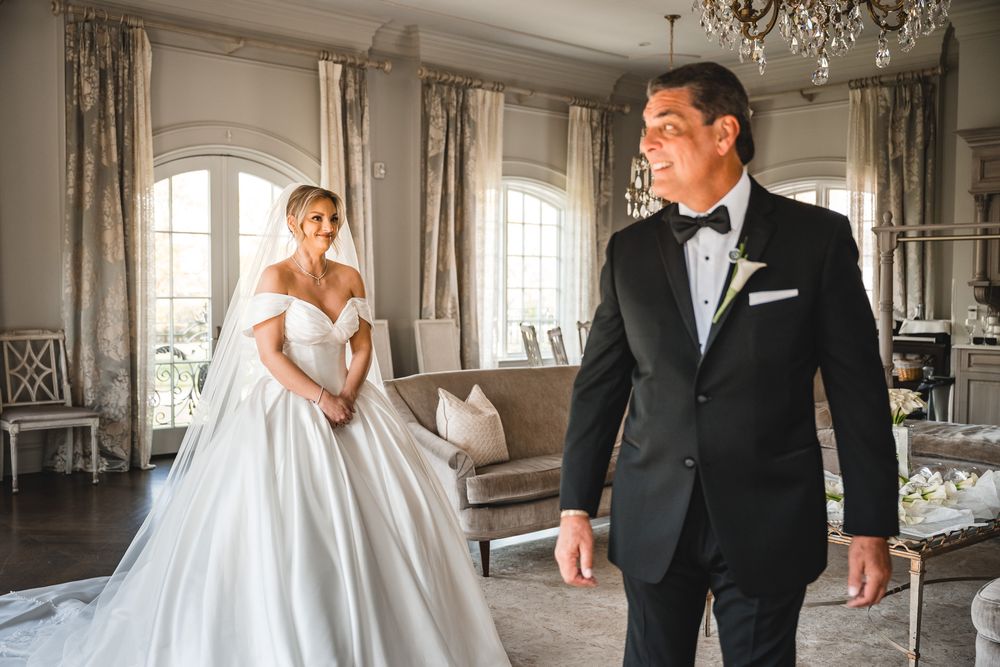 Groom in tuxedo seeing bride in ball gown for first look in elegant venue.