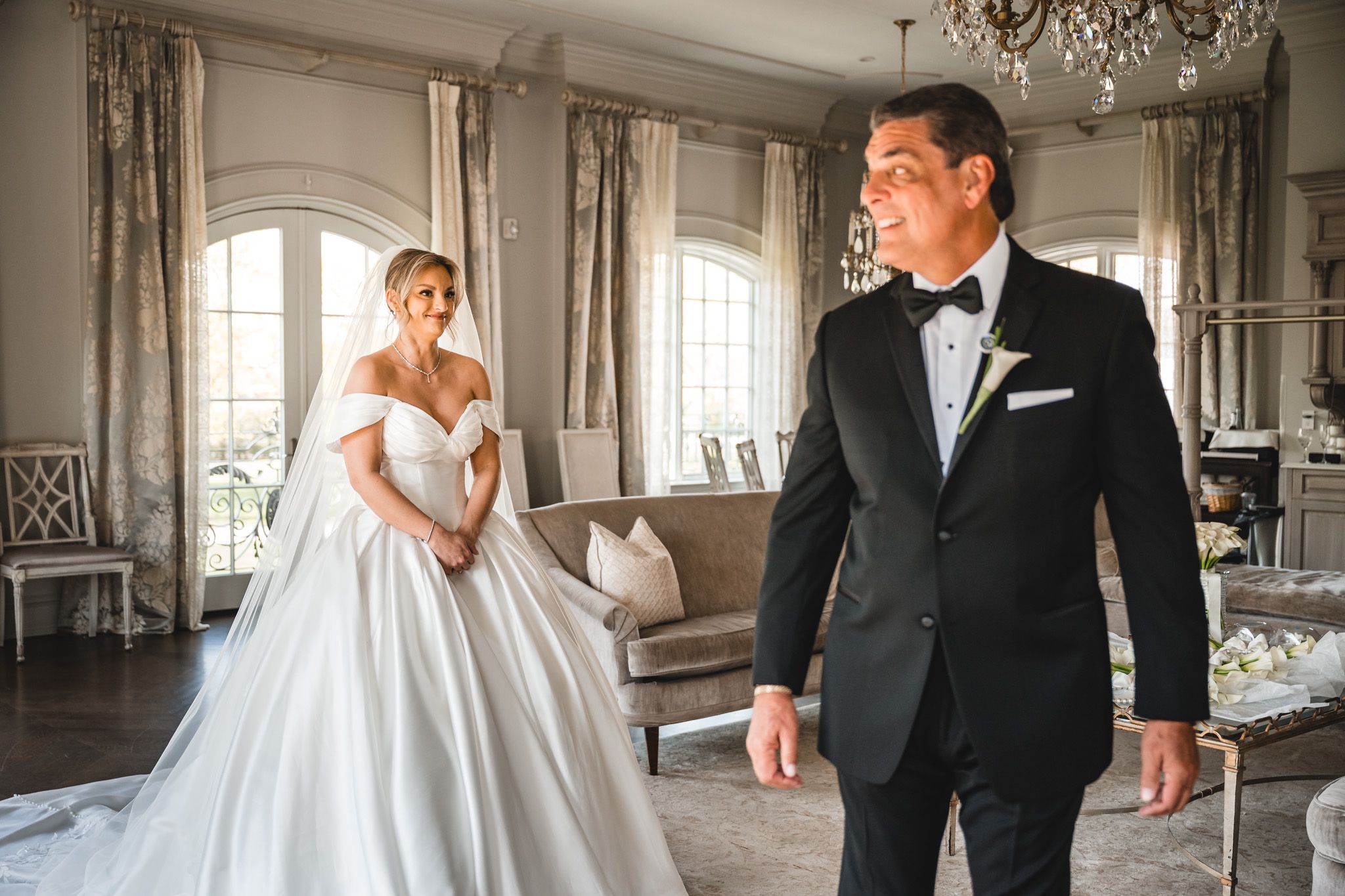 Groom in tuxedo seeing bride in ball gown for first look in elegant venue.