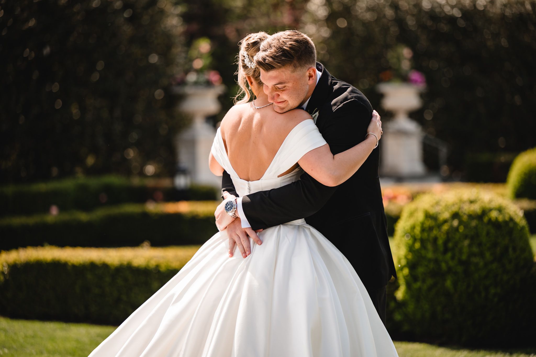 Bride and groom share a romantic embrace in a lush garden on their wedding day.