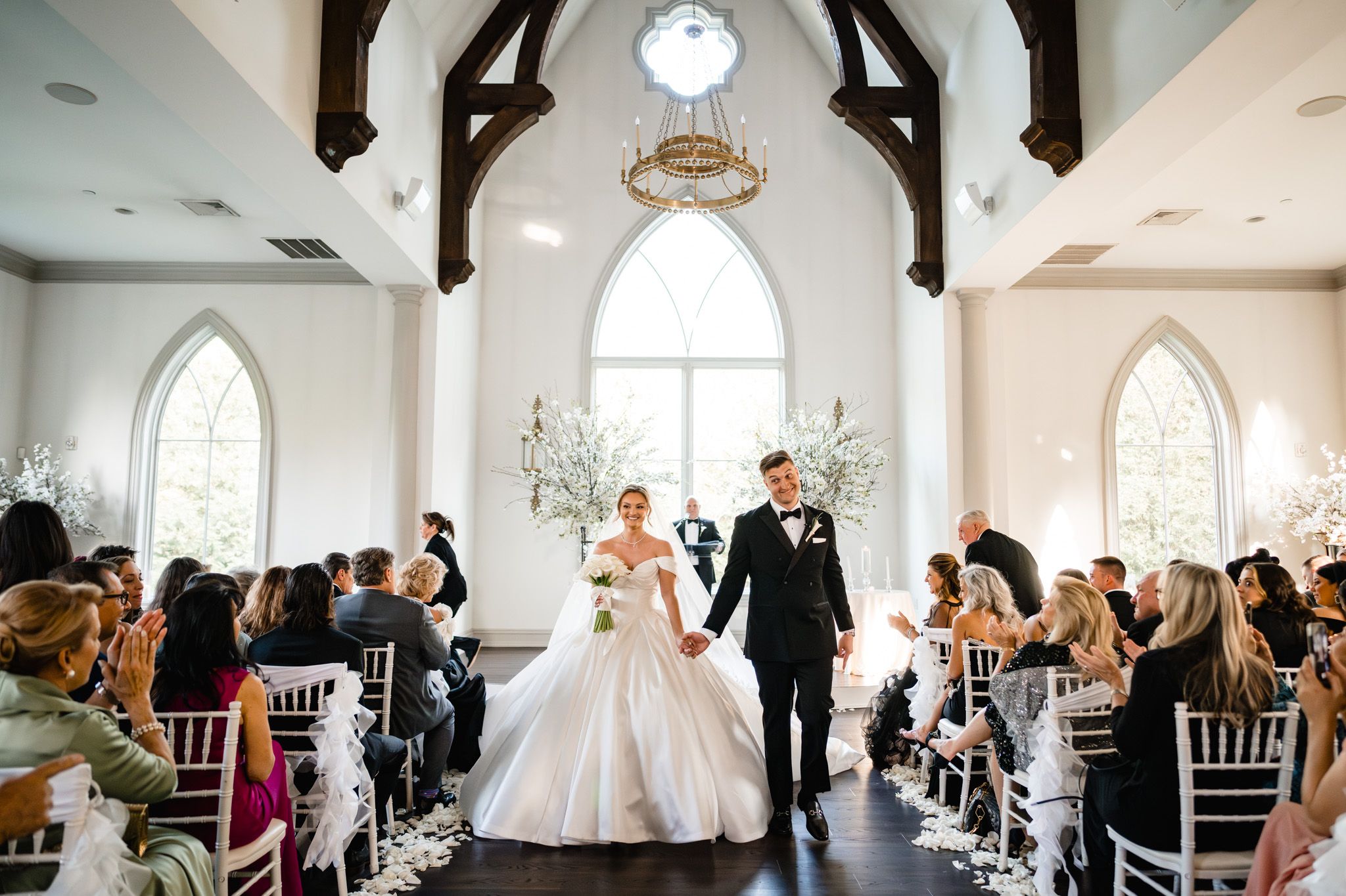 Bride and groom walk down the aisle in a beautiful white chapel wedding ceremony.